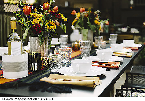 Flower vases with crockery arranged on table in backyard