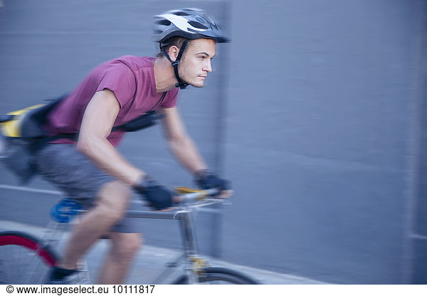 Focused bicycle messenger with helmet on the move