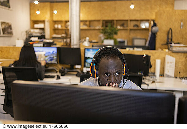 Focused businessman in headset working at computer in office