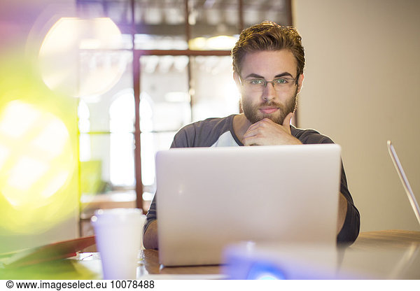 Focused casual businessman working at laptop in office