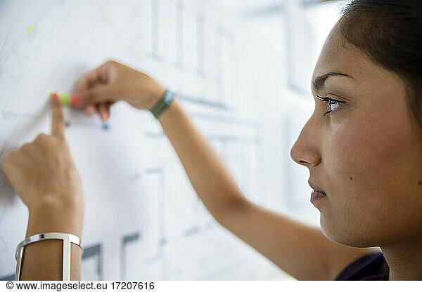 Focused female architect working with graph on white board in office