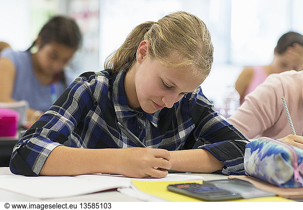 Focused junior high school student doing homework in classroom