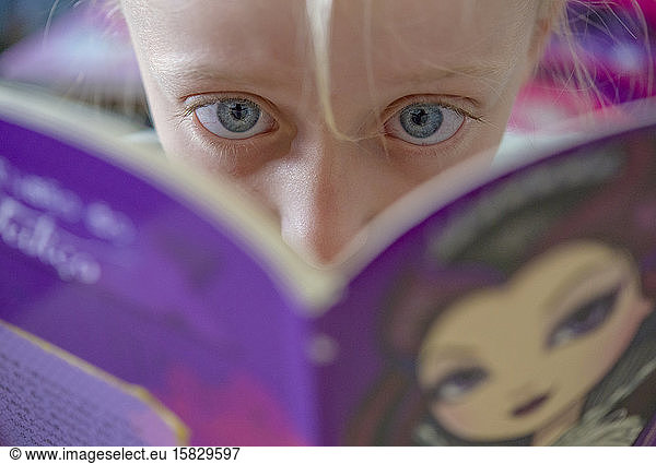 Focused little girl with big green eeditorial reading childrenÂ´s book
