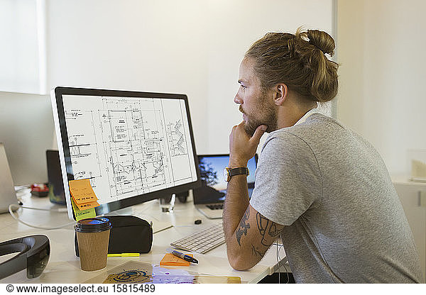 Focused male architect viewing digital blueprint on computer