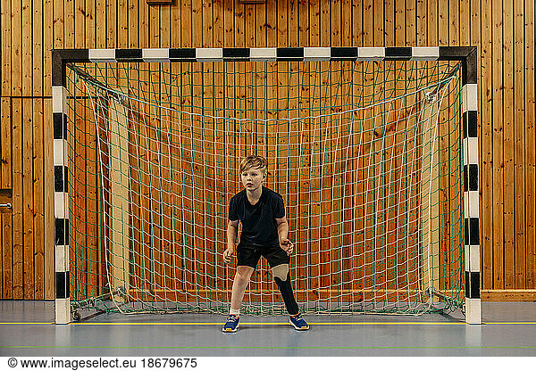 Focused male goalie with disability standing in front of net at sports court