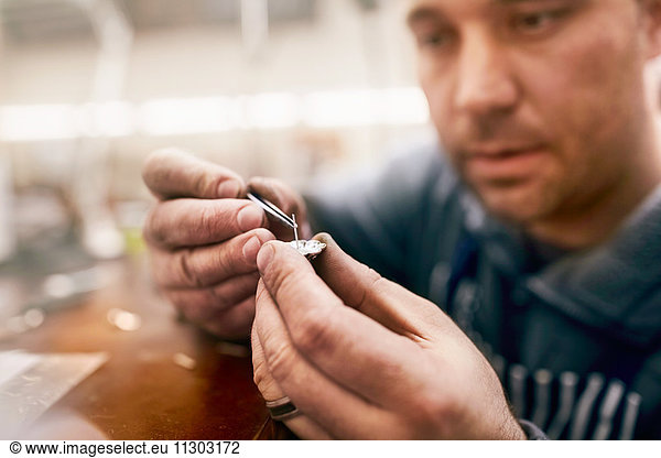 Focused male jeweler assembling jewelry in workshop