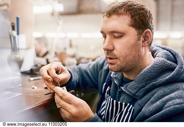 Focused male jeweler making jewelry in workshop