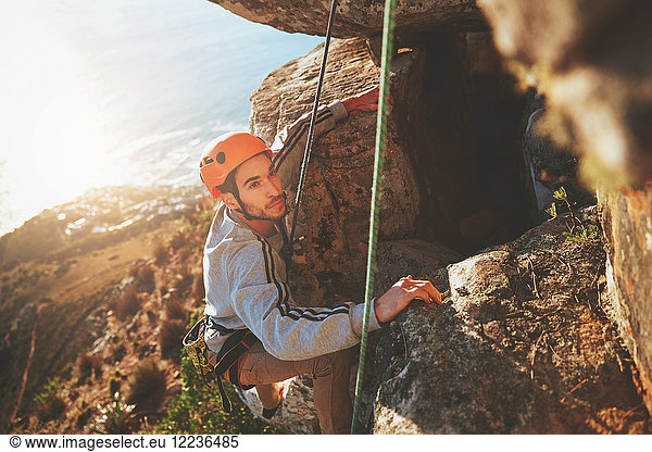 Focused male rock climber climbing rock