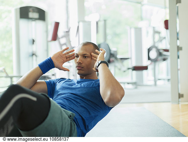 Focused man doing sit-ups at gym