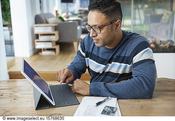 Focused man paying bills at digital tablet