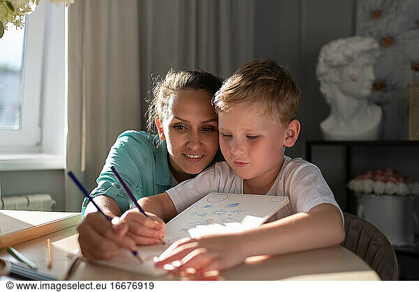 Focused mother and son sketching in planner