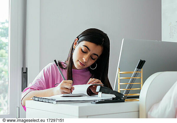 Focused teen studying at desktop in personal room