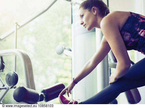 Focused woman stretching leg at gym