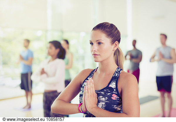 Focused woman with hands at prayer position in yoga class