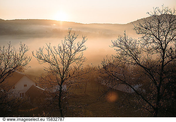 Foggy sunrise landscape in autumn mountains village