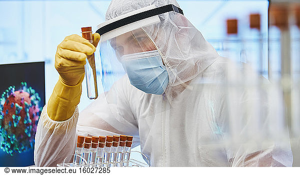 Fokussierter männlicher Wissenschaftler mit Reagenzglas erforscht Coronavirus