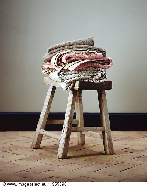 Folded blankets on small wooden stool