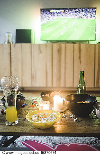 Food and drink on table against TV at living room
