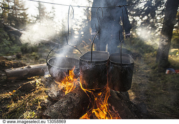 Food being cooked in utensils over bonfire