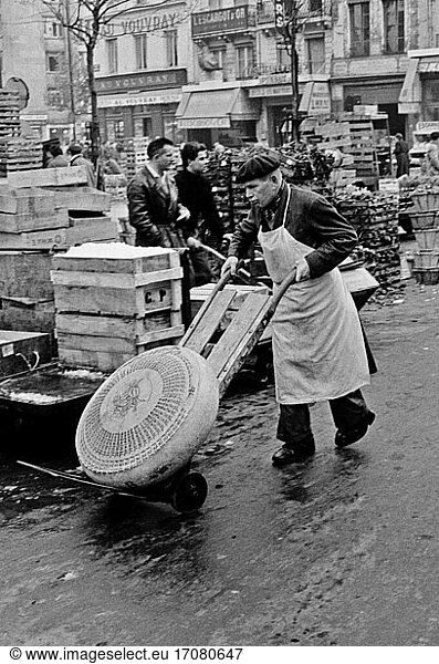 Food / Markets. A man transporting Gruyère cheese at Les Halles market in Paris. Photo  1958.