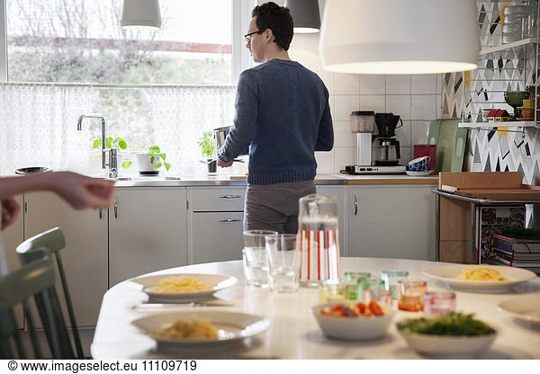 Food served on table against man standing by kitchen counter at home