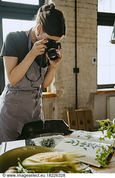 Food stylist photographing through digital camera while working in studio