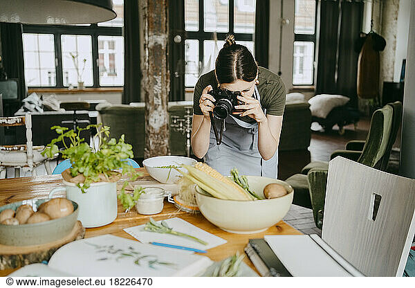 Food stylist photographing using digital camera in studio