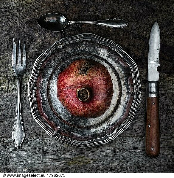 Foodfotografie  Stillleben  Granatapfel auf alten Teller und Besteck  von oben  Studioaufnahme  Symbolfoto