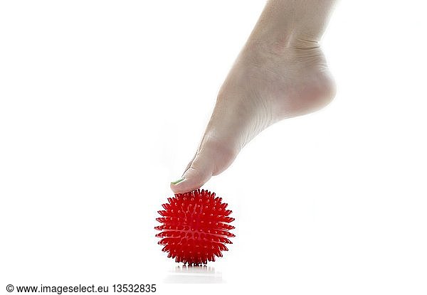 Foot standing with toes on a red massaging ball