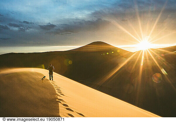 footprints in the dune of a hiker and his dog at sunset