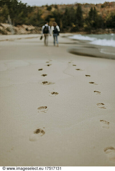 Footsteps in sand of couple walking along sandy beach  Michigan.