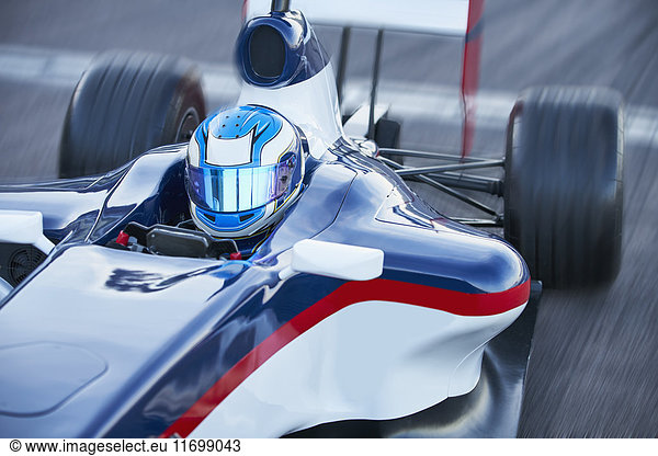 Formula one race car driver in helmet on sports track