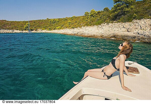 Foto einer Touristin in einem Luxusurlaub auf den Pakleni-Inseln  Insel Hvar  Dalmacija  Dalmatien  Kroatien. Dies ist ein Foto einer weiblichen Touristin im Luxusurlaub  die auf einem Boot auf den Pakleni-Inseln in der Nähe der Insel Hvar in Dalmacija  Dalmatien  Kroatien  ein Sonnenbad nimmt.