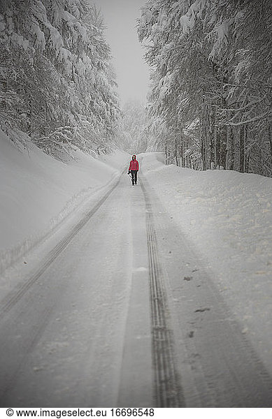 Fotograf geht über verschneite Straße