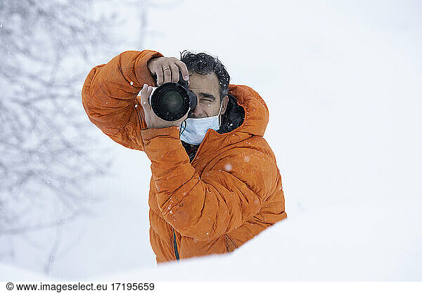 Fotograf mit einer Maske mitten im Schneefall