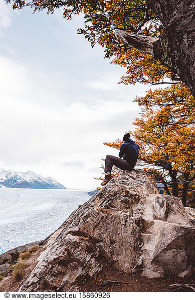 Fotograf sitzt auf Fels an Gletschern