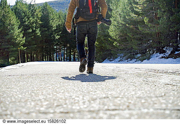 Fotograf zu Fuss auf einer verschneiten Bergstrasse