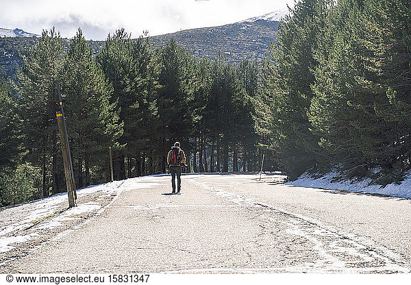 Fotograf zu Fuss auf einer verschneiten Bergstrasse