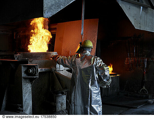 Foundry worker burning metal in furnace at workshop