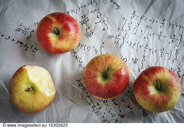 Four apples lying on paper with formulas  studio shot