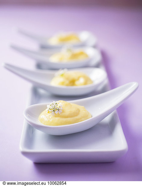 Four custard desserts on china spoons