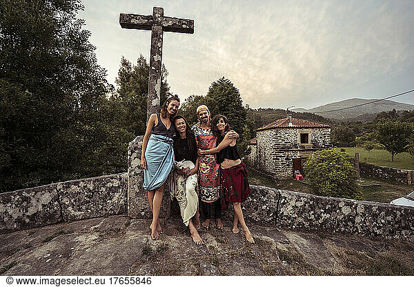 Four friends and lovers hug and smile on stone bride in Portugal