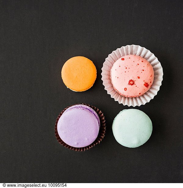 Four macarons against black background  overhead view