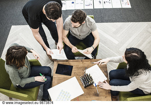 Four people seated at a table using coloured pens on paper  colleagues at a planning meeting.
