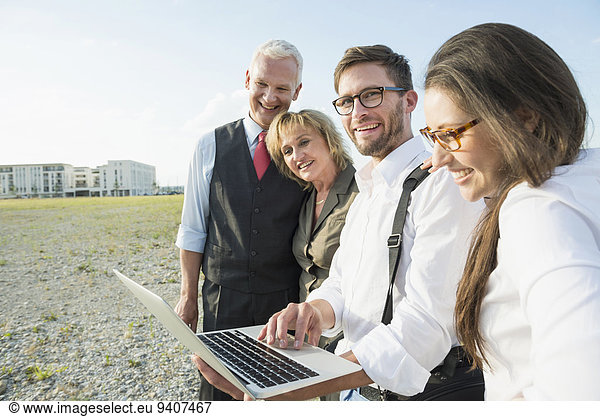 Four smiling people with laptop at development area