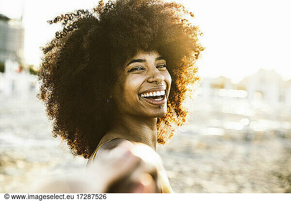 Fröhliche Frau mit Afrofrisur am Strand