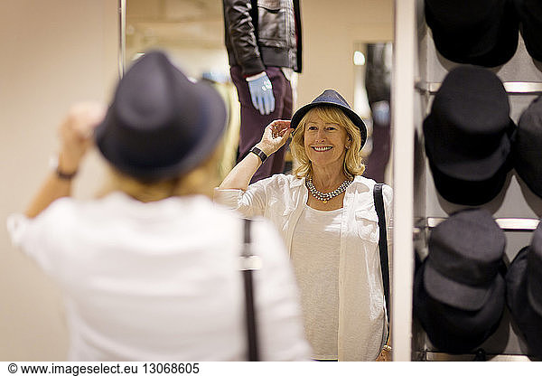Fröhliche Frau mit Hut im Bekleidungsgeschäft