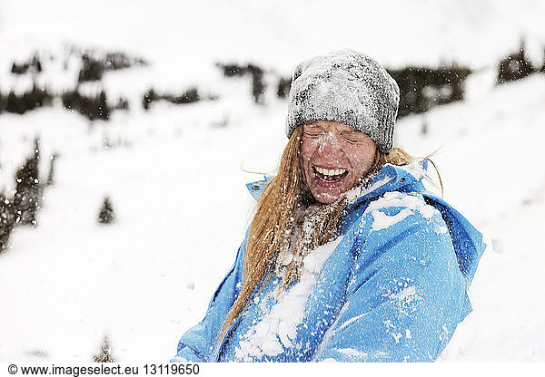 Fröhliche Frau mit Schnee bedeckt
