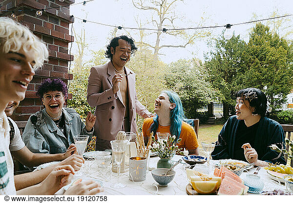 Fröhliche Freunde der LGBTQ-Gemeinschaft  die sich bei einer Dinnerparty im Hinterhof amüsieren