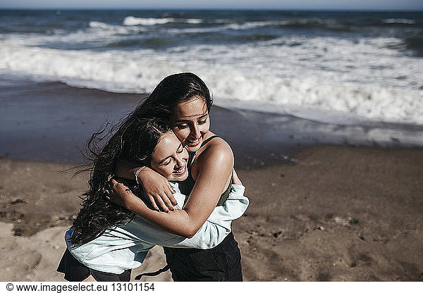 Fröhliche Freunde umarmen sich am Strand